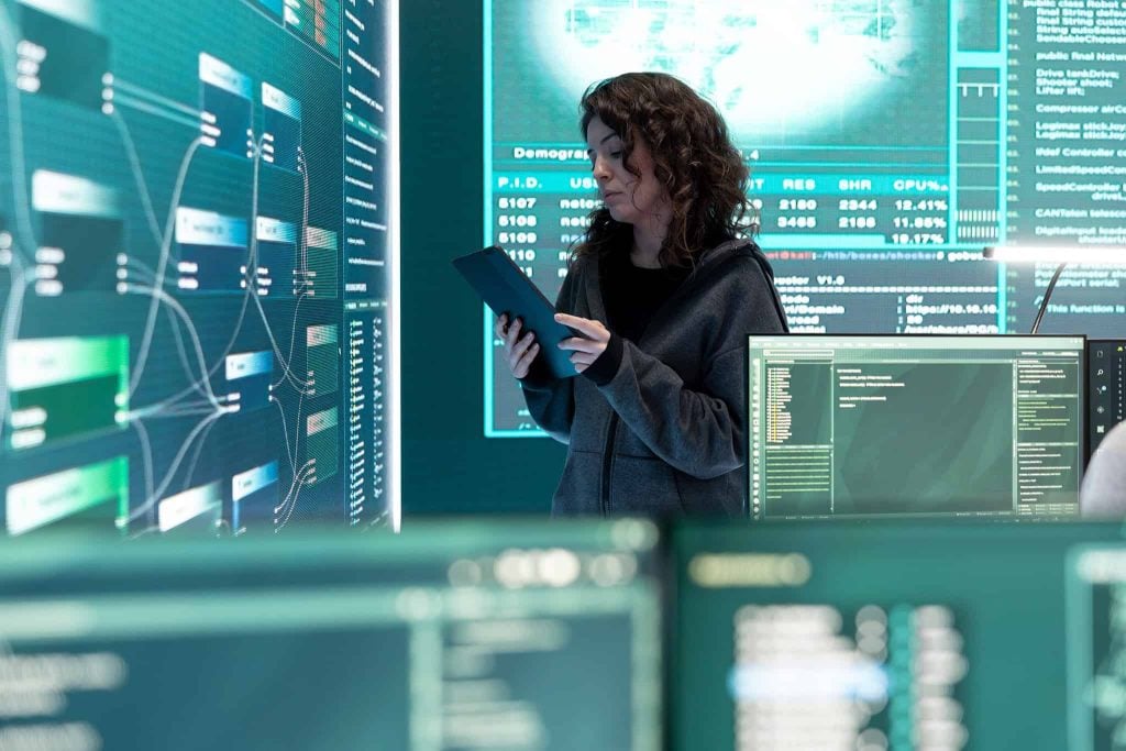 woman reviewing an tablet inside a room with monitoring screens