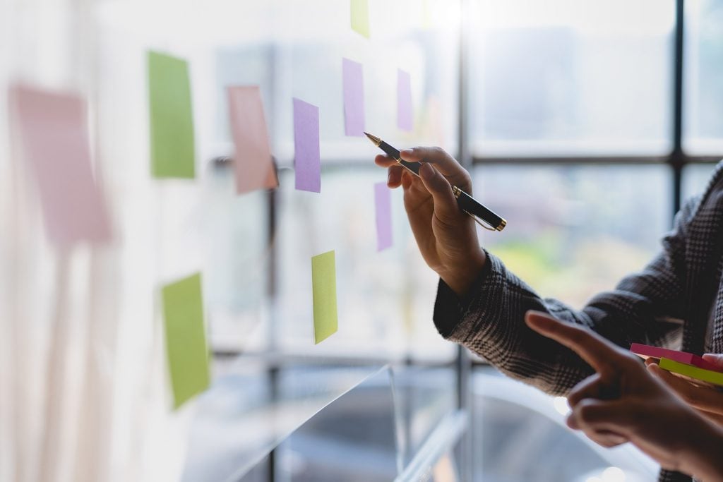 person near a whiteboard with sticky notes